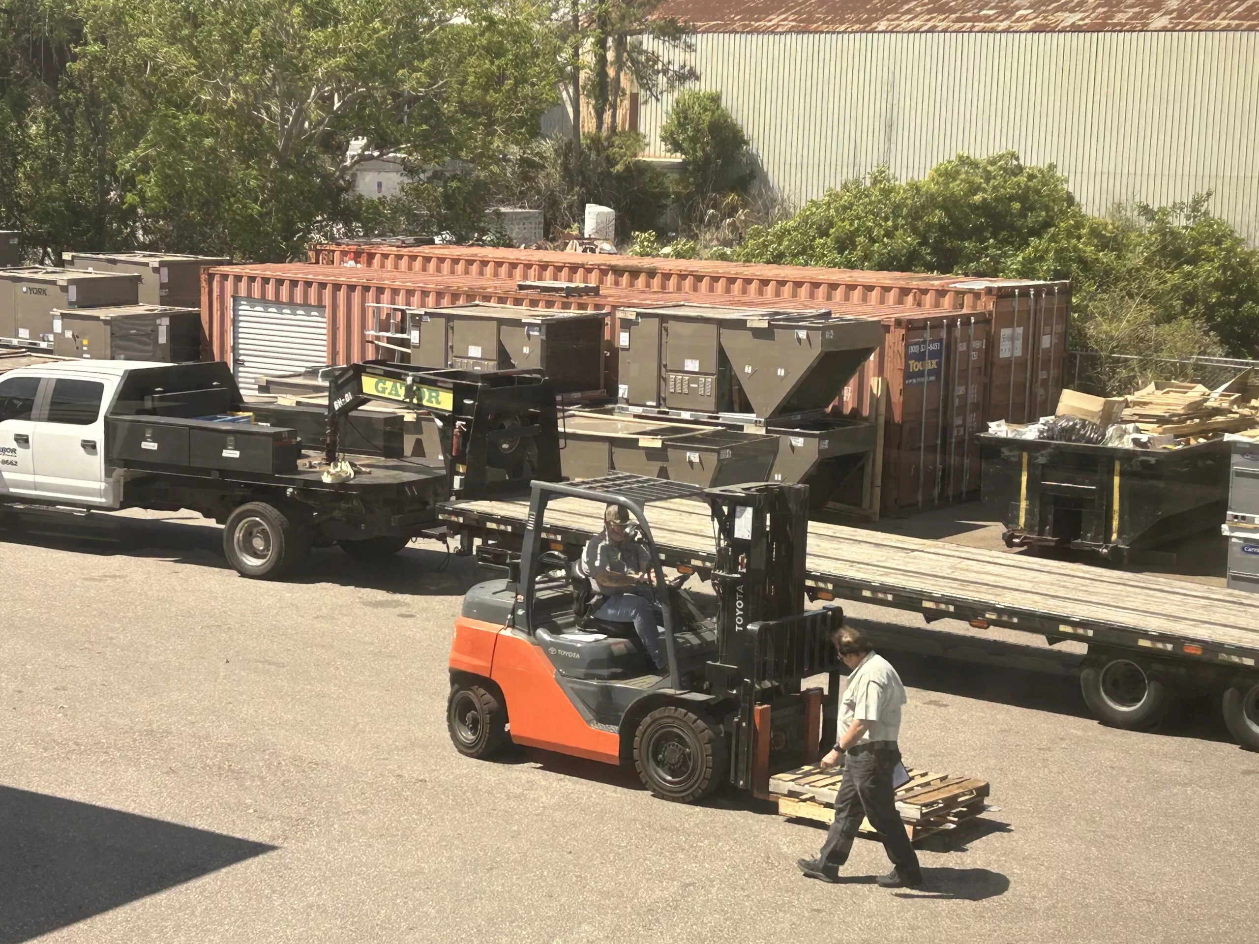 Bob Case conducting in-person forklift operations training in Tampa for a private sector client, with industrial equipment and shipping containers in the background.